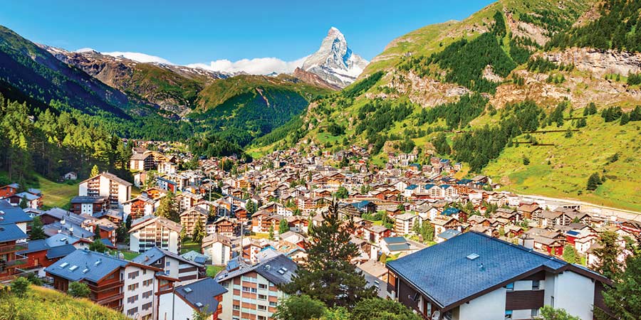The charming Swiss resort of Zermatt features many traditional wooden chalets, and the snowy Matterhorn sits behind it.