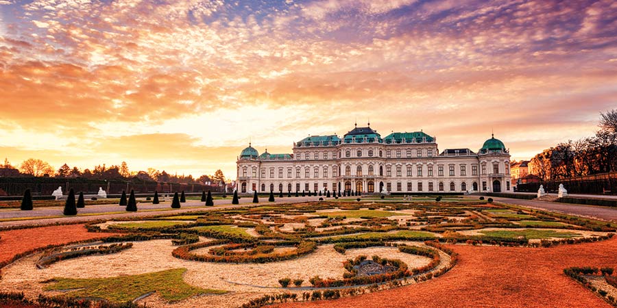 The Palace and royal gardens of Vienna are lit by a beautiful orange sunset.