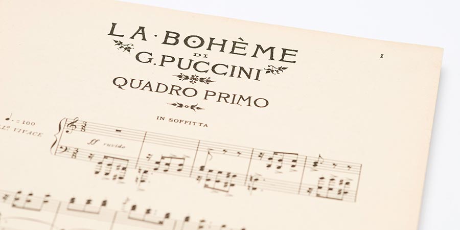 Sheet music on white background of song La Bohème composed by Giacomo Puccini on older stained paper.
