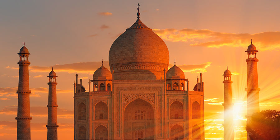 The beautiful Taj Mahal surrounded by a beautiful orange sunset.
