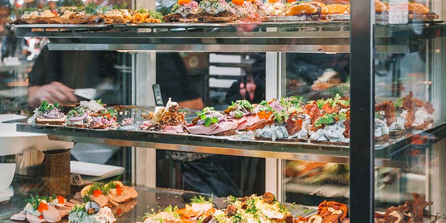 Traditional Smorrebrod open faced sandwiches are displayed in a cafe window.