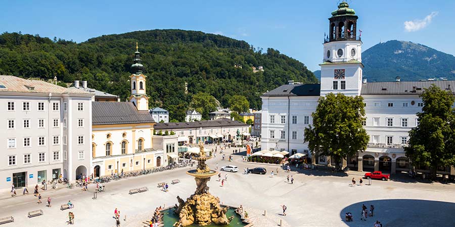 The Residenzplatz of Salzburg is busy with tourists on a bright sunny day