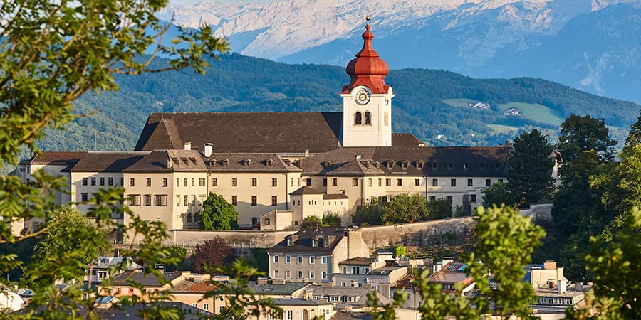 The striking clock tower of the Nonnberg Abbey sits in front of a beautiful Austrian mountain range.