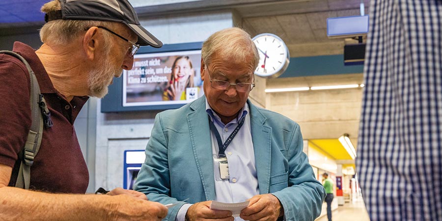 A Great Rail Journeys tour manager assists a customer with their ticket in the tain station.