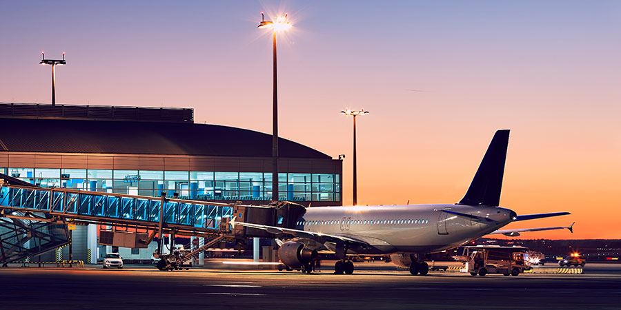 A plane waits at the airport gate on an evening.