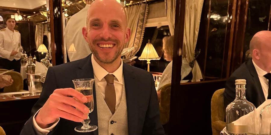 James holds his drink while sitting in the dining car of the Venice Simplon-Orient-Express.