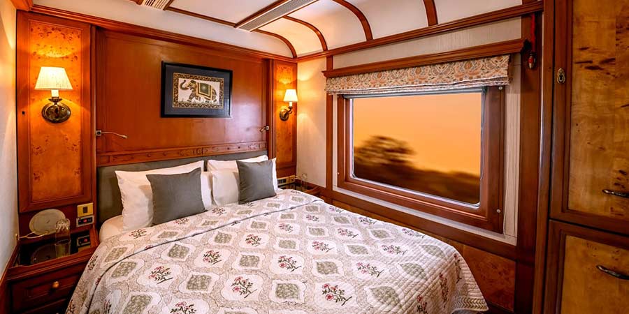 One of the cabins onboard the Deccan Odyssey, it is well decorated with rich wood tones and a large bed.