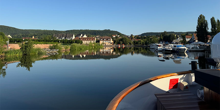  View of the canal from the barge, with small boats and rural scenery in the background. 