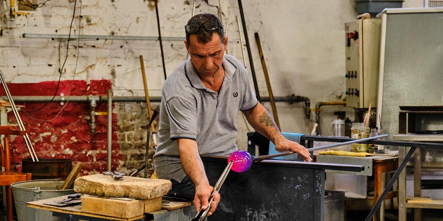 A man gives a Murano glass-blowing demonstration.