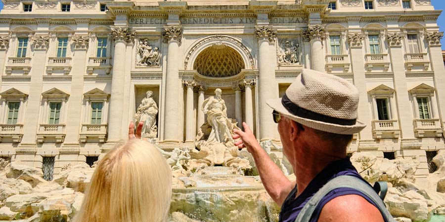 Two people view the Trevi Fountain of Rome.